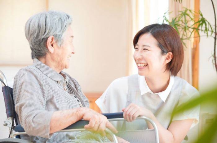 高齢の女性と歯科スタッフが笑顔で会話しているイメージ