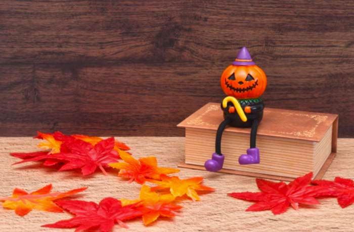 ハロウィンのかぼちゃの人形と紅葉の落ち葉、秋の季節感を表す写真